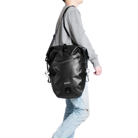 Black Corsino Journey Pannier Bag 27L carried on a shoulder with the included strap, demonstrating its versatile off-bike transport options.