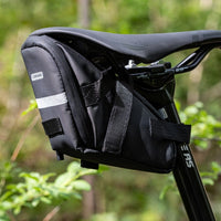 Saddle Bag in black, attached to a bike saddle and seat post, made of water-resistant polyester. Dimensions: 19x11x11cm, weight: 80g. Side view.
