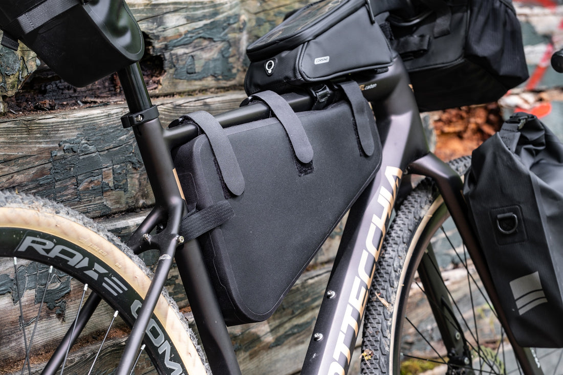 Black bike frame bag attached to a gravel bike frame, made of waterproof 840D Nylon TPU. Dimensions: 39.5x6x23/10 cm, weight: 330g. Features a 5-strap fixation system for stability, a 3-layer support structure to maintain shape under load, and is both waterproof and scratch-resistant.