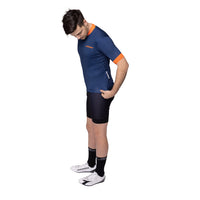 Side profile of a model wearing the navy Corsino Tremblant jersey, highlighting the longer pro sleeve length, aerodynamic build, and comfortable athletic cut