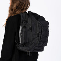 Corsino Pannier Bag 75L in black, made from water-resistant 500D PVC Twill Fabric, shown being used as a backpack with shoulder straps.