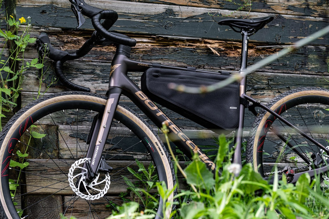 Waterproof black Corsino Excursion Waterproof Bike Frame Bag secured to a gravel bike frame, made from durable 840D Nylon TPU. Equipped with a 3-layer support structure to ensure shape retention under load, and offers both waterproofing and scratch resistance.