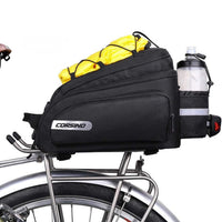 Side view of the Corsino Adventure 12L bicycle commuter luggage mounted on a rear rack, showing the top elastic band holding a yellow rain cover and the rear bottle holder