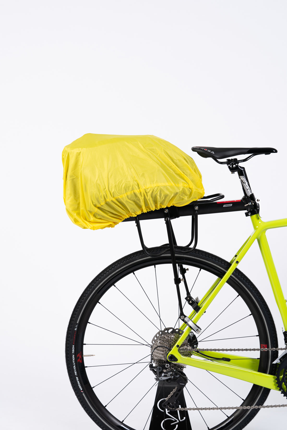 The Corsino Quest 17L trunk cargo bag securely mounted to a bicycle rack, fully protected by the included yellow rain cover to keep cycling essentials dry during wet weather rides
