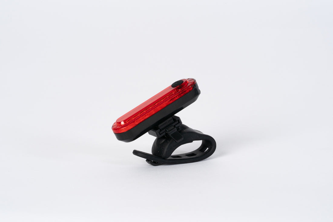 Corsino Spark rear bike light securely mounted on a cyclist's seatpost during a ride. The blazing 50-lumen output and 12-hour Super Flash mode guarantee maximum visibility and safety on open roads from dusk until dawn