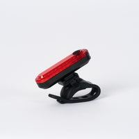 Corsino Spark rear bike light securely mounted on a cyclist's seatpost during a ride. The blazing 50-lumen output and 12-hour Super Flash mode guarantee maximum visibility and safety on open roads from dusk until dawn